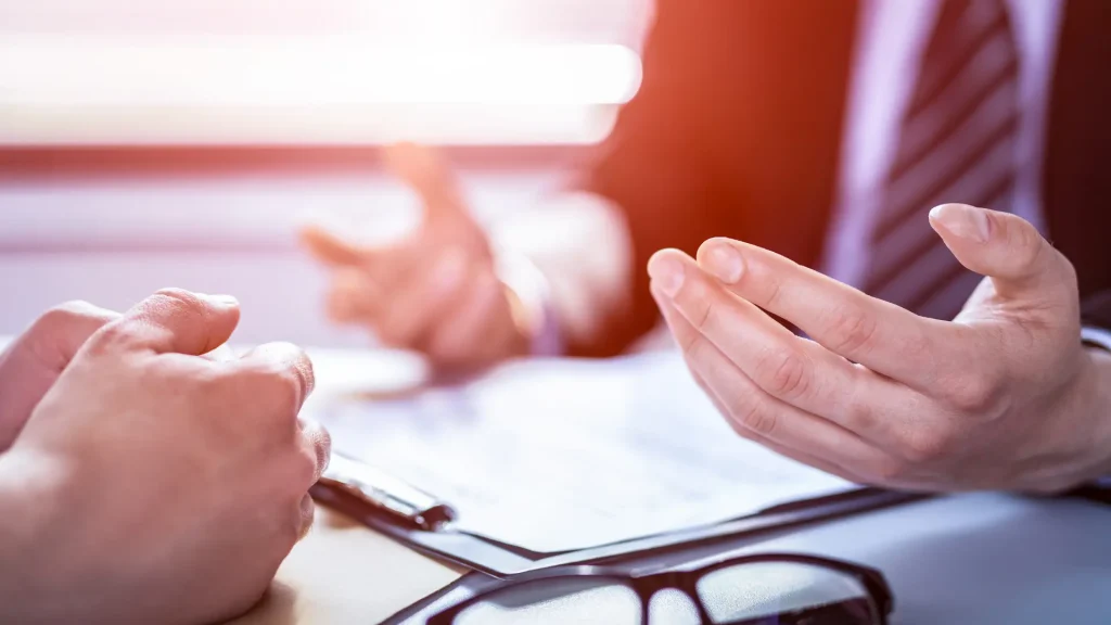 Close-up of hands in a discussion over legal documents on a desk